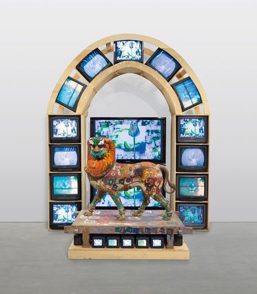 A statue of a lion, surrounded by TV screens
